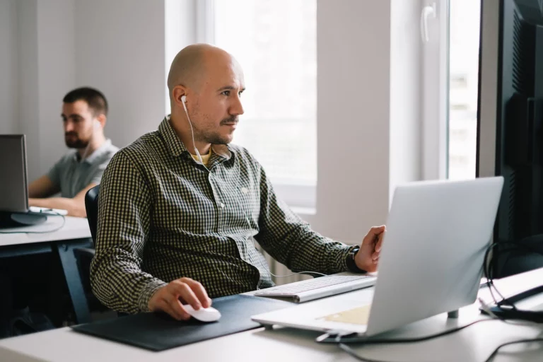 man with earphones working on computer sitting in office