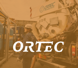 A man standing besides heavy machinery while wearing protective gear